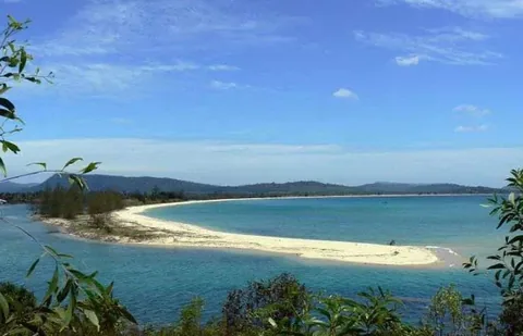 Doi cat trang uon cong nhoi ra vung nuoc xanh ngoc, bao quanh boi doi nui xanh gan Phu Quoc.