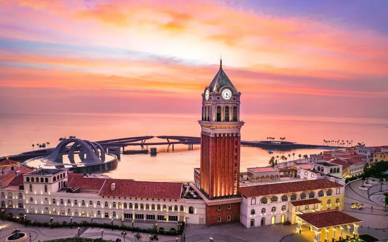 Tháp đồng hồ cao nổi bật trên khu phố ven biển kiểu Venice ở Phú Quốc dưới bầu trời hoàng hôn rực rỡ.