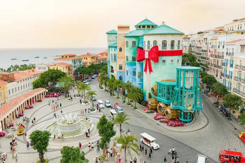 Những tòa nhà kiểu châu Âu đầy màu sắc và đài phun nước tạo nên quảng trường sôi động ở Phú Quốc lúc hoàng hôn.