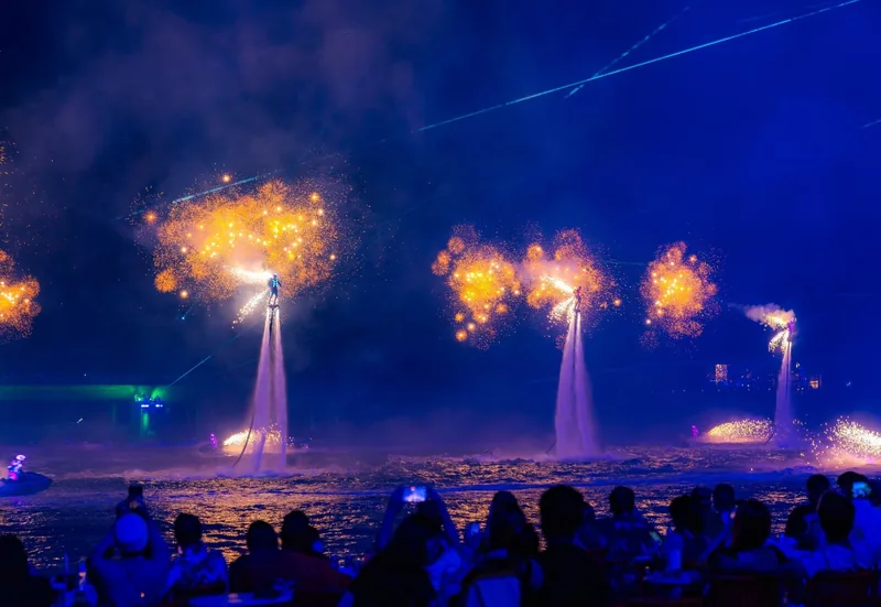 Những người biểu diễn flyboard bắn pháo hoa lên bầu trời đêm trong buổi trình diễn trên mặt nước ở Phú Quốc trước đám đông.